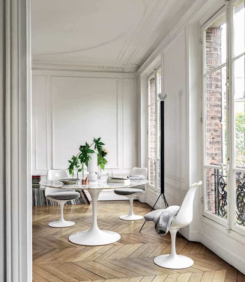 Una moderna mesa de comedor blanca en plástico blanco con bases de pedestal en un interior de casa clásico