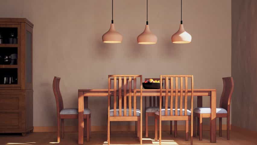 Foto de tres luces colgantes sobre una mesa de madera y sillas