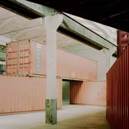 Amaa pilas de contenedores de transporte en la fábrica italiana para crear un espacio dentro de un espacio