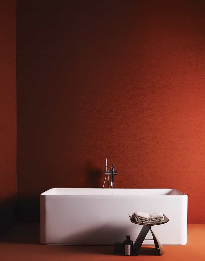 Un baño de color naranja cálido con bañera blanca independiente