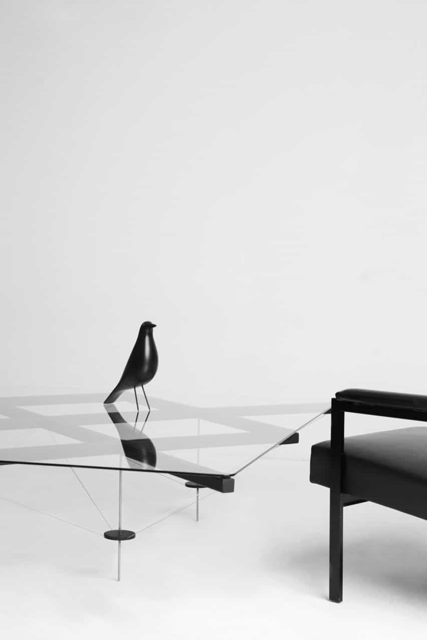 TT_01 mesa con un pájaro decorativo negro sentado en la parte superior y un sillón negro al lado
