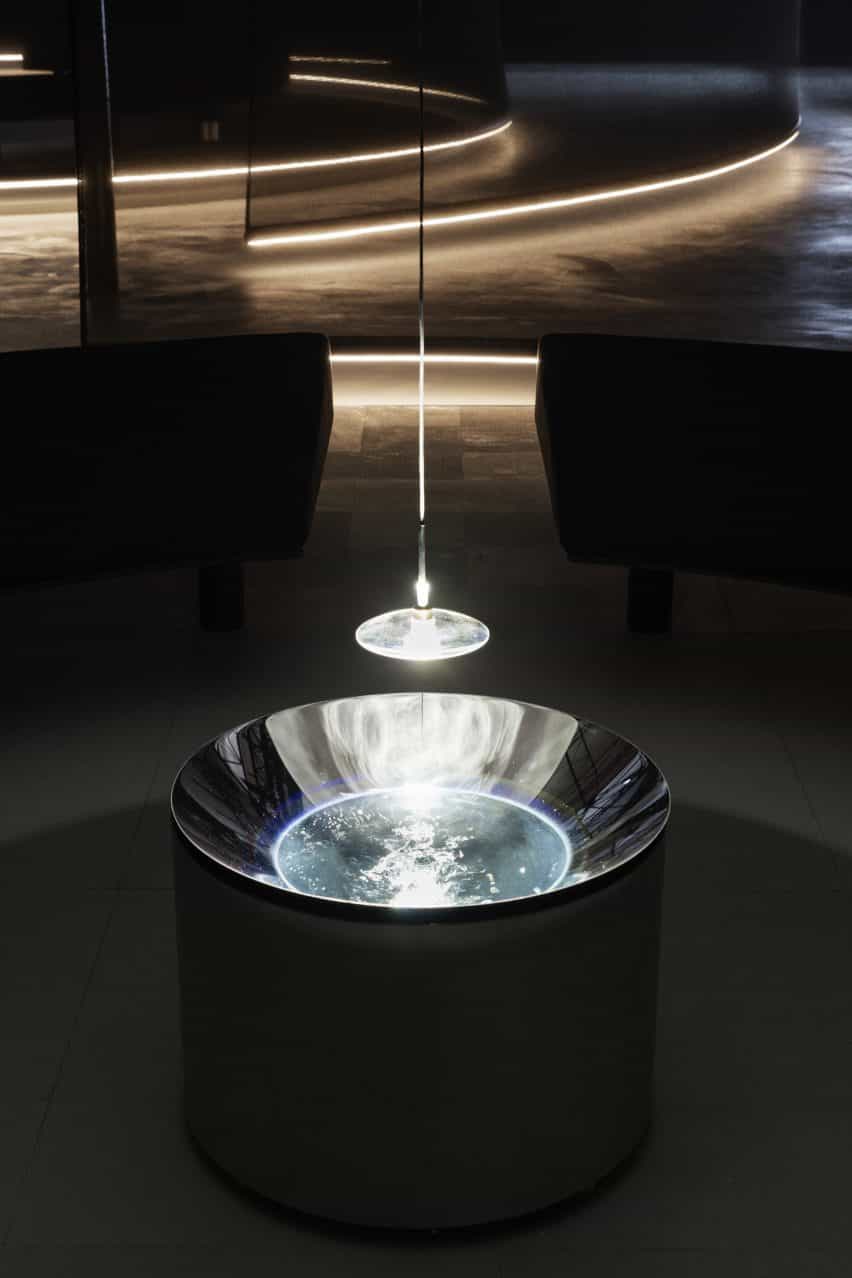 Luz y lente colgando sobre un lavabo de acero por Lachlan Turczan