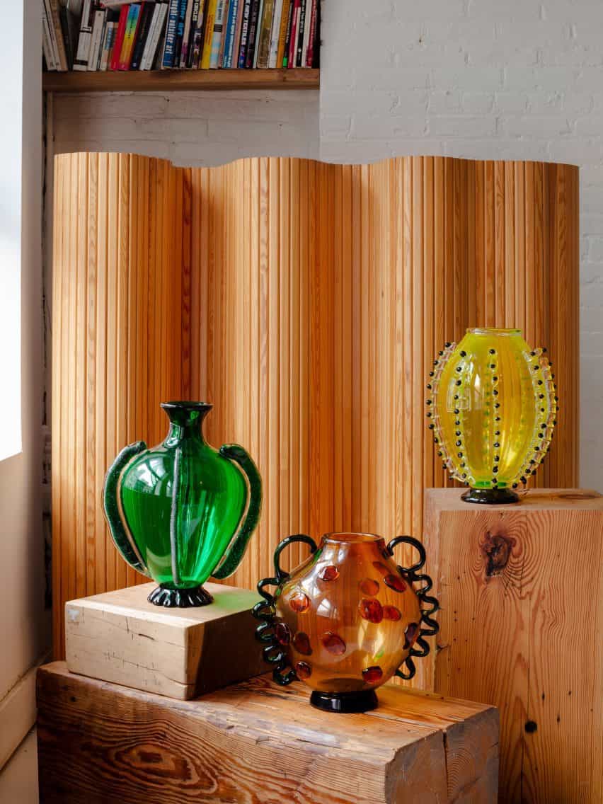 Tres jarrones de vidrio con forma de verdura sobre soportes de madera
