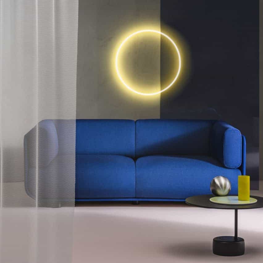 Fotografía que muestra un sofá azul cobalto con luz de anillo amarilla detrás