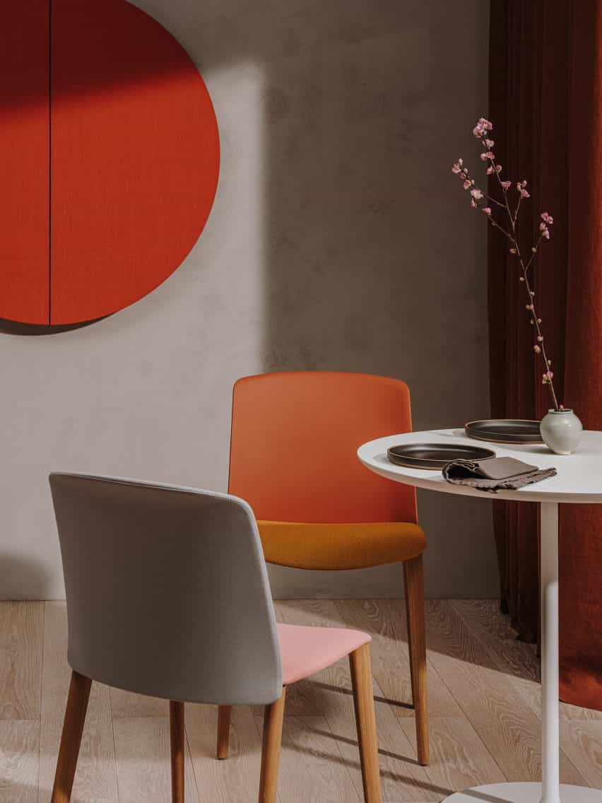 Silla Mixu roja orientada hacia adelante que se muestra con el respaldo de una silla Mixu gris y rosa, rodeada por una mesa con flores en ella