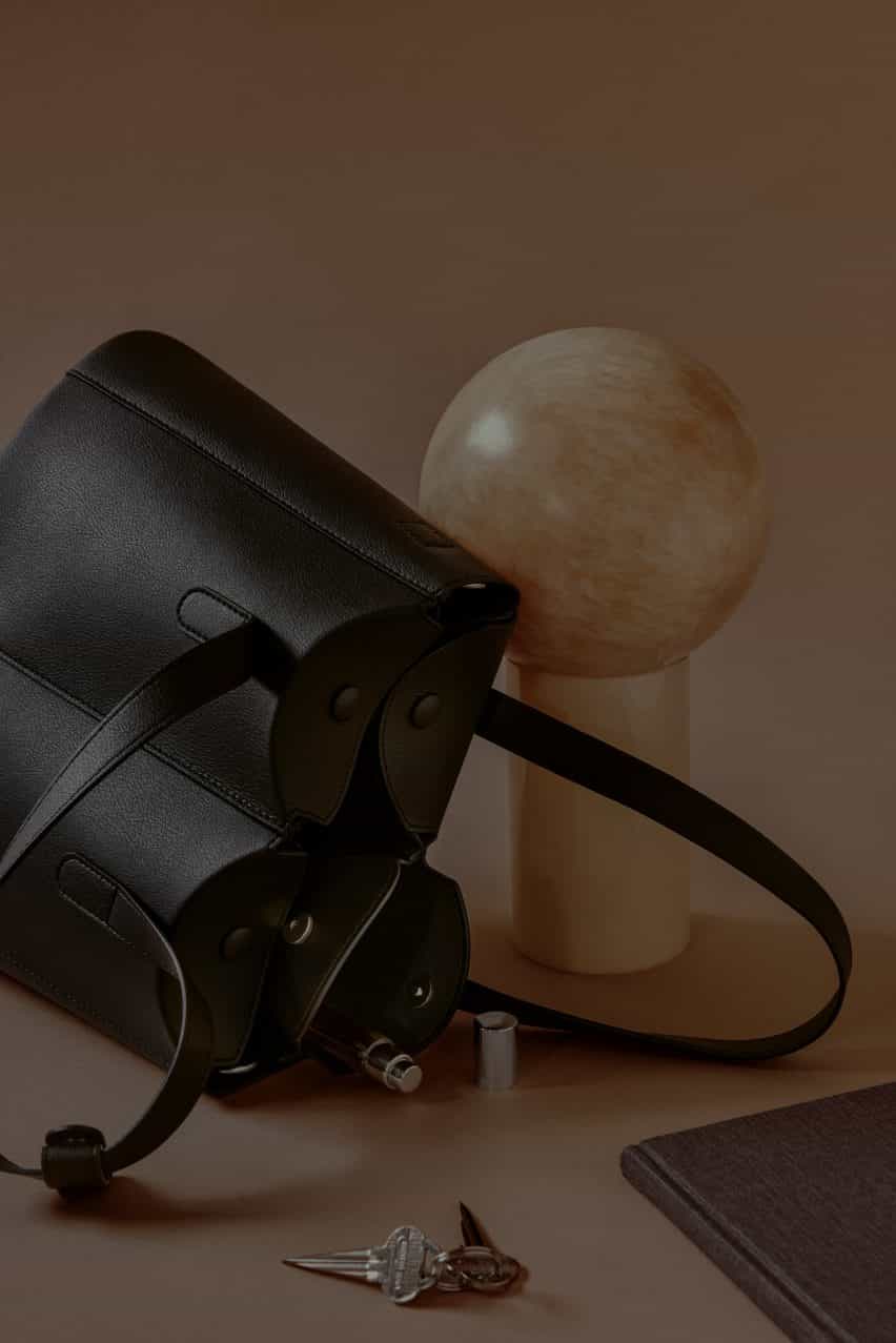 Foto de un bolso de mano negro en su lado con objetos que se derraman de los bolsillos