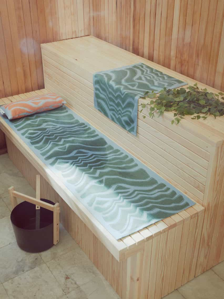 Asiento de sauna de madera con toallas estampadas en azul y verde