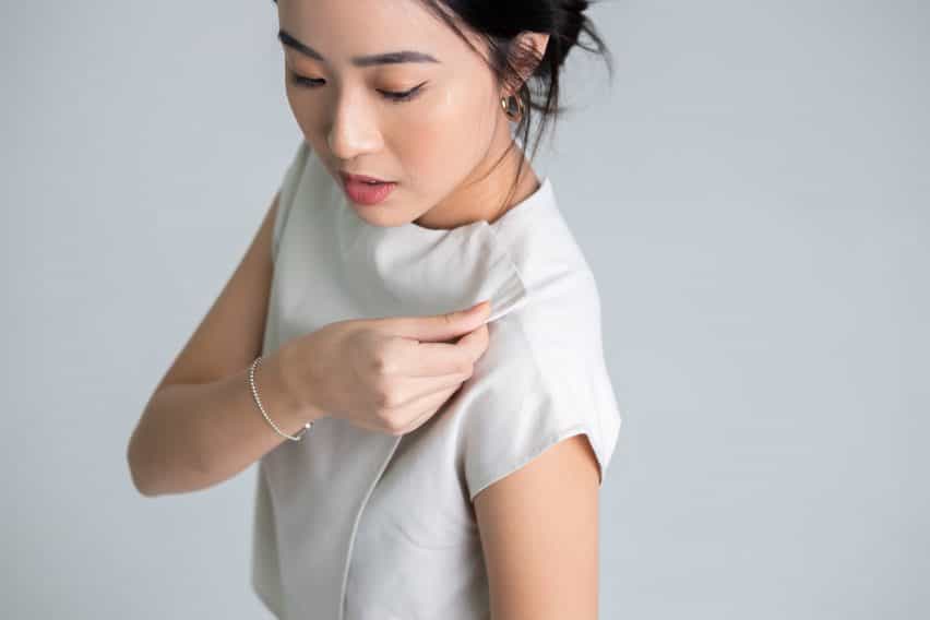 Foto de una modelo con la blusa bidireccional de Will&Well, con un primer plano del cierre de velcro en la línea del cuello