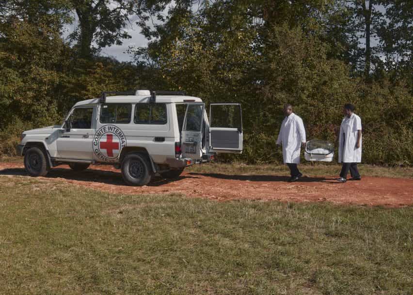 Dos médicos llevan una incubadora a una ambulancia.