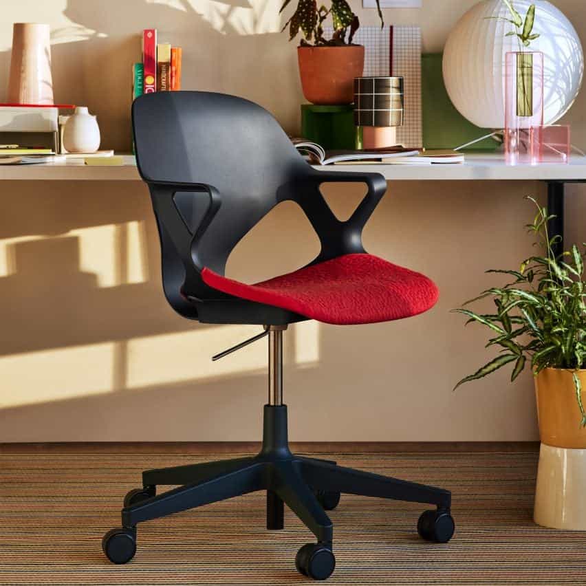 Silla Zeph negra con asiento tapizado rojo en un escritorio de casa